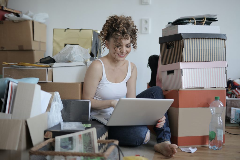 woman using a laptop while sitting on the floor with boxes