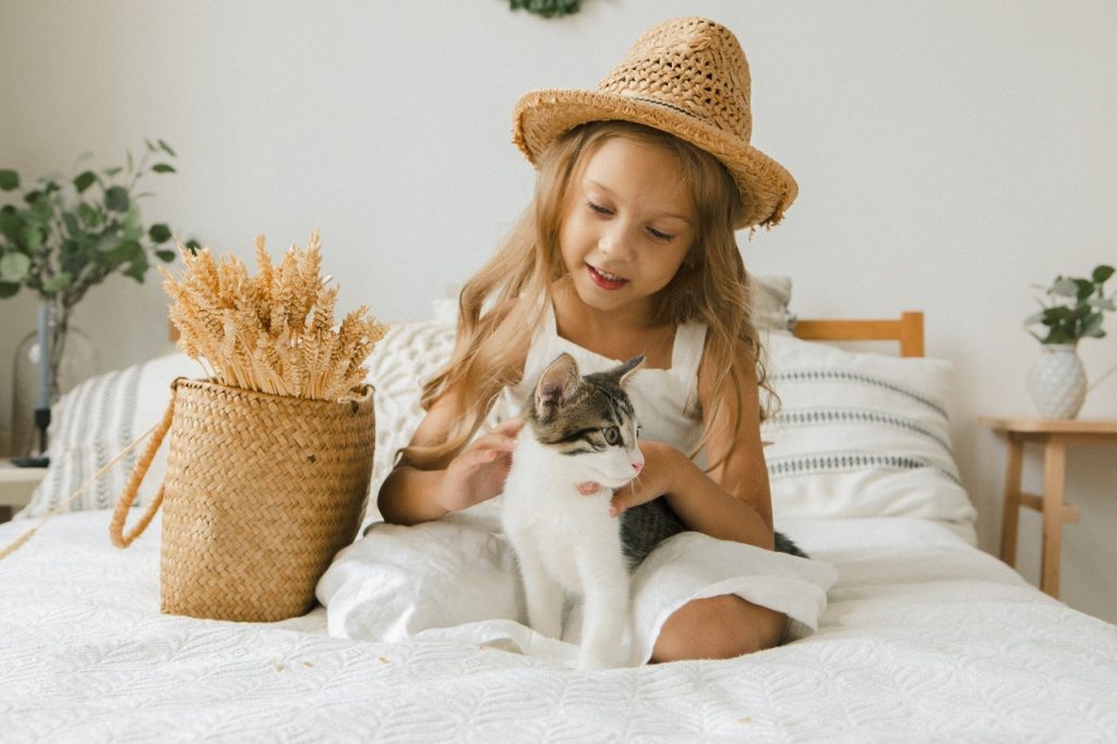 little girl playing with cat on bed