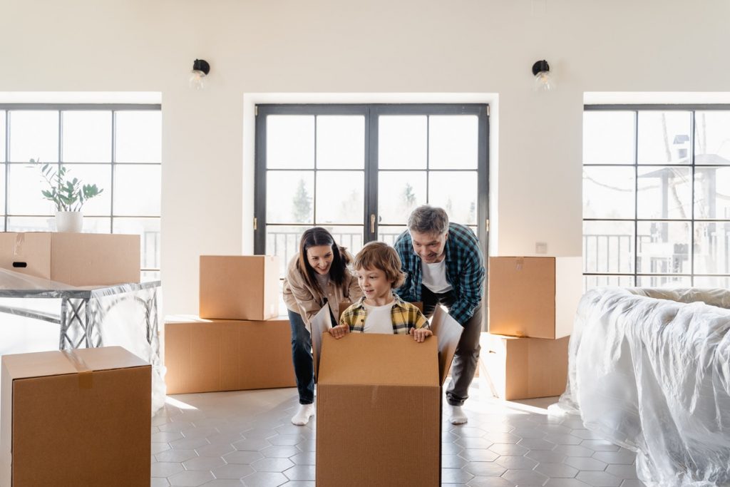 a little boy in a box being pushed by a woman and a man