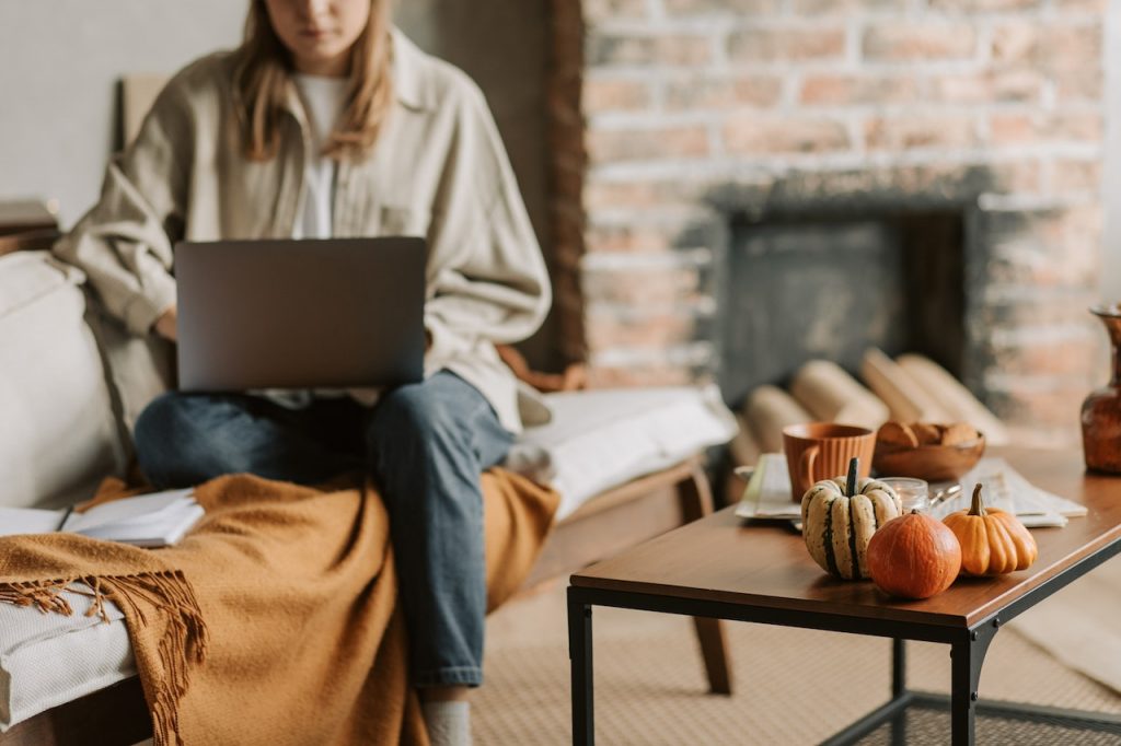 a woman sitting on the couch while using a laptop