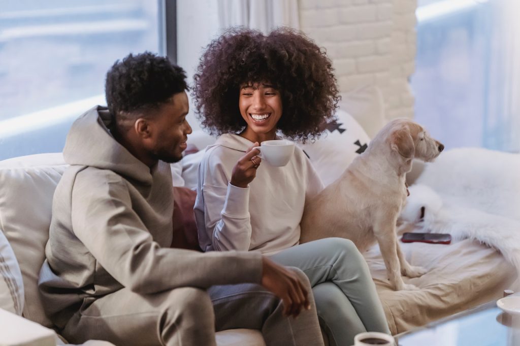 a man and woman sitting on the couch with their dog